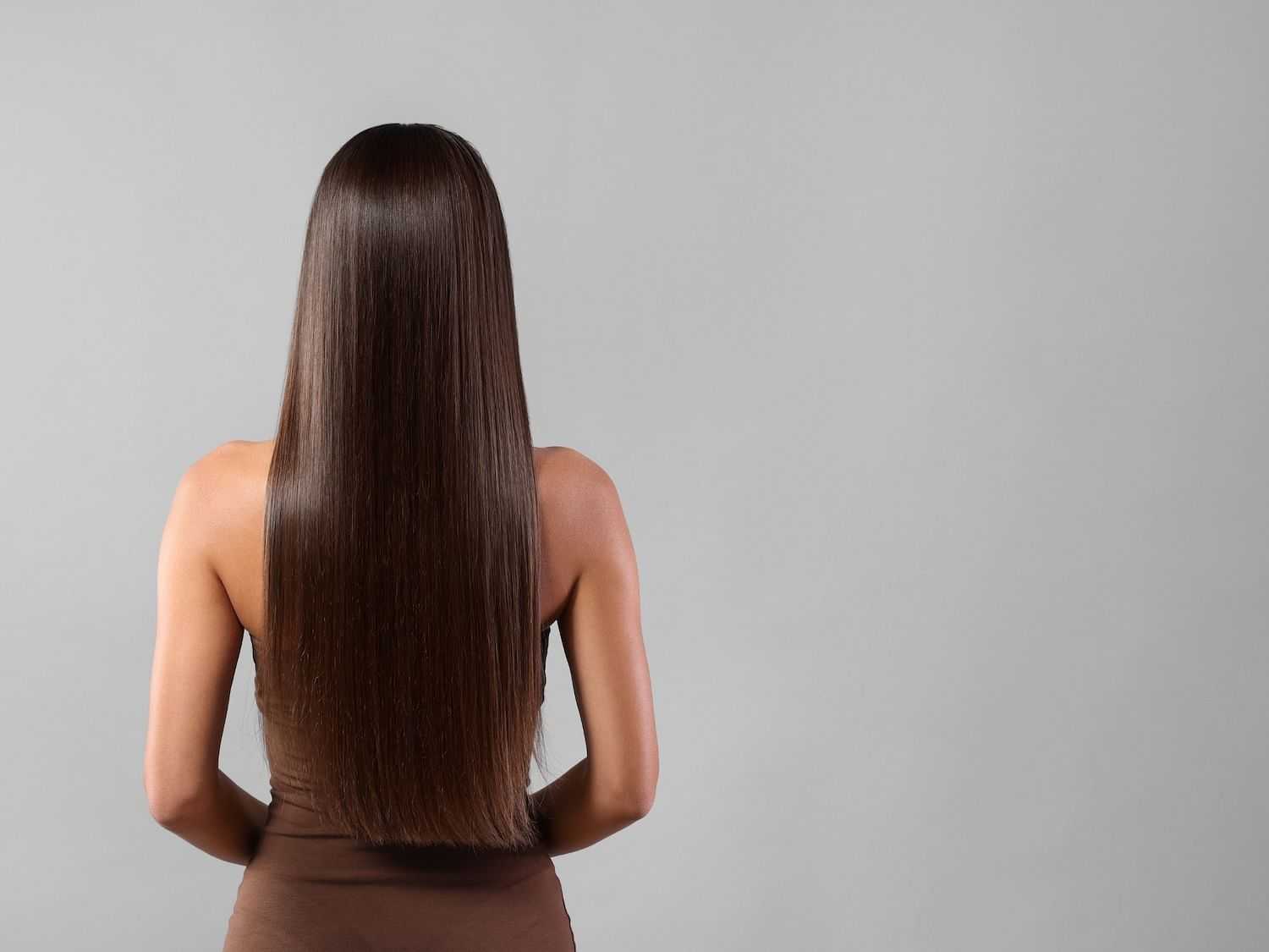 Woman with long straight brown hair, back facing camera.