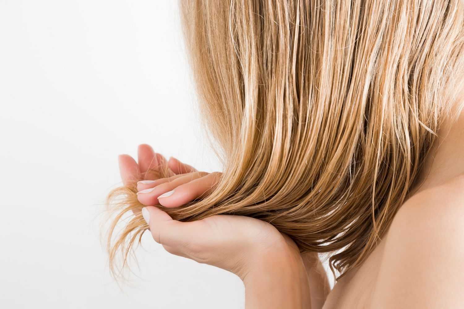 Woman examining her hair ends against a white background.
