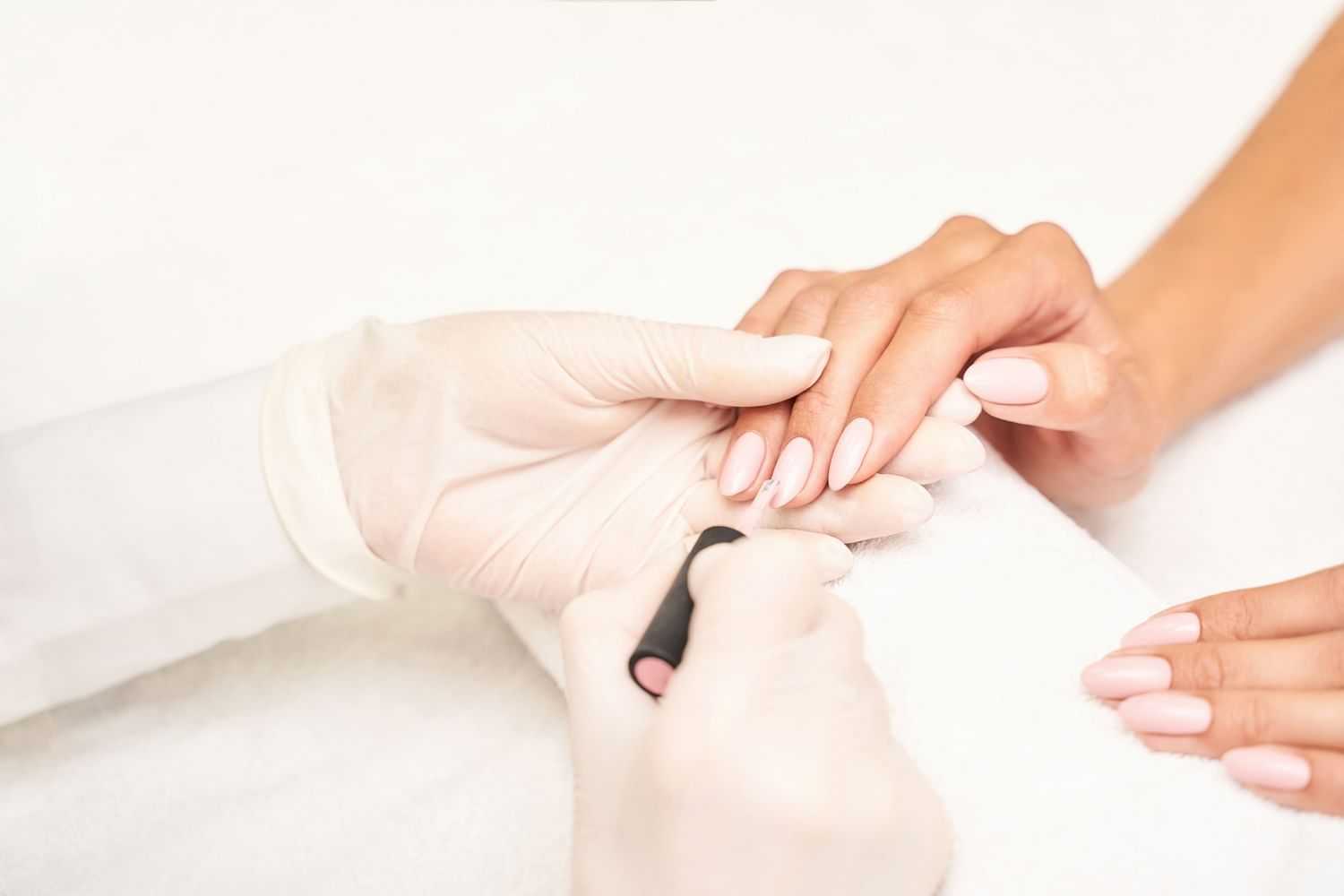 A nail technician manicures a client's nails.