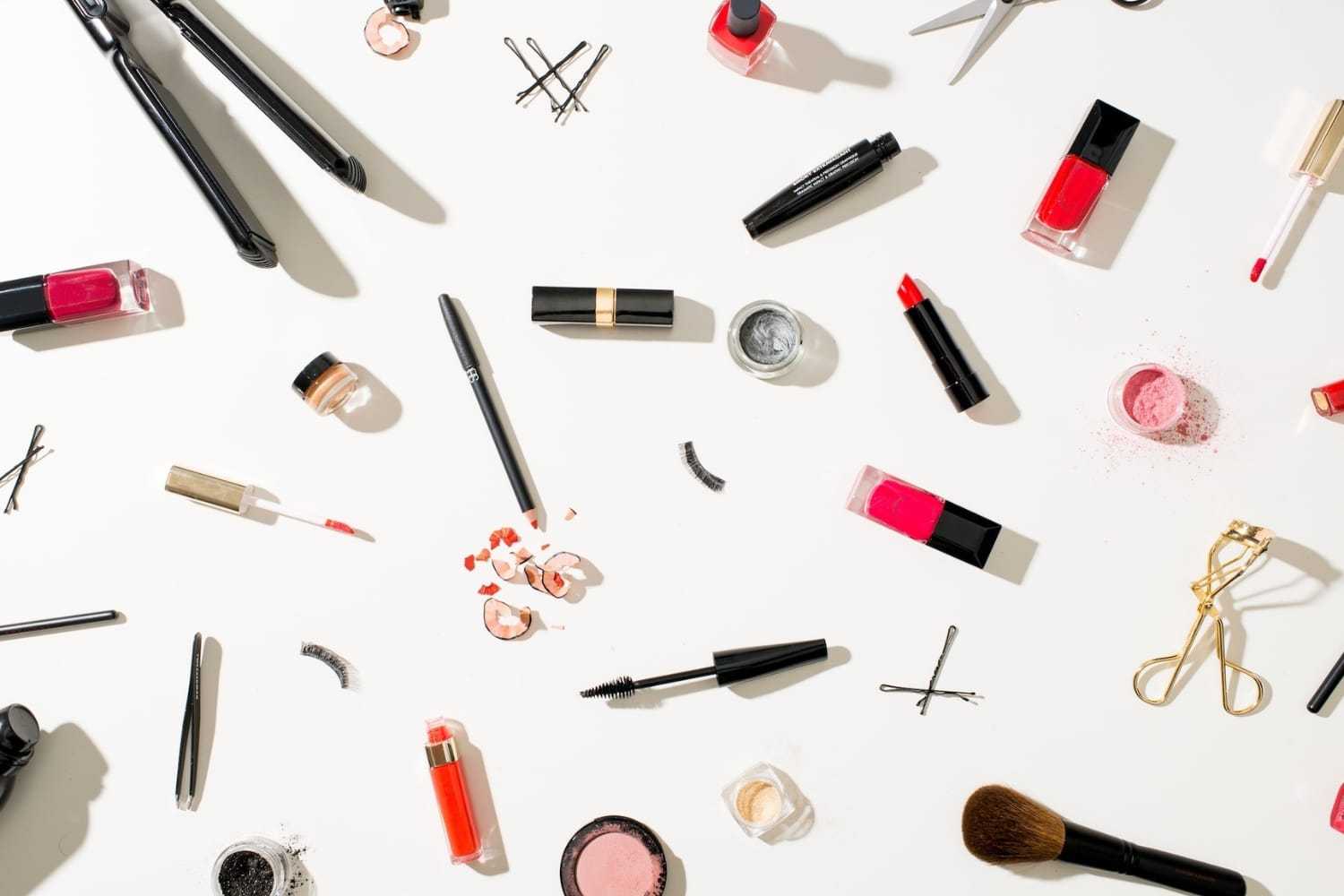 Assorted makeup products scattered on a white background.