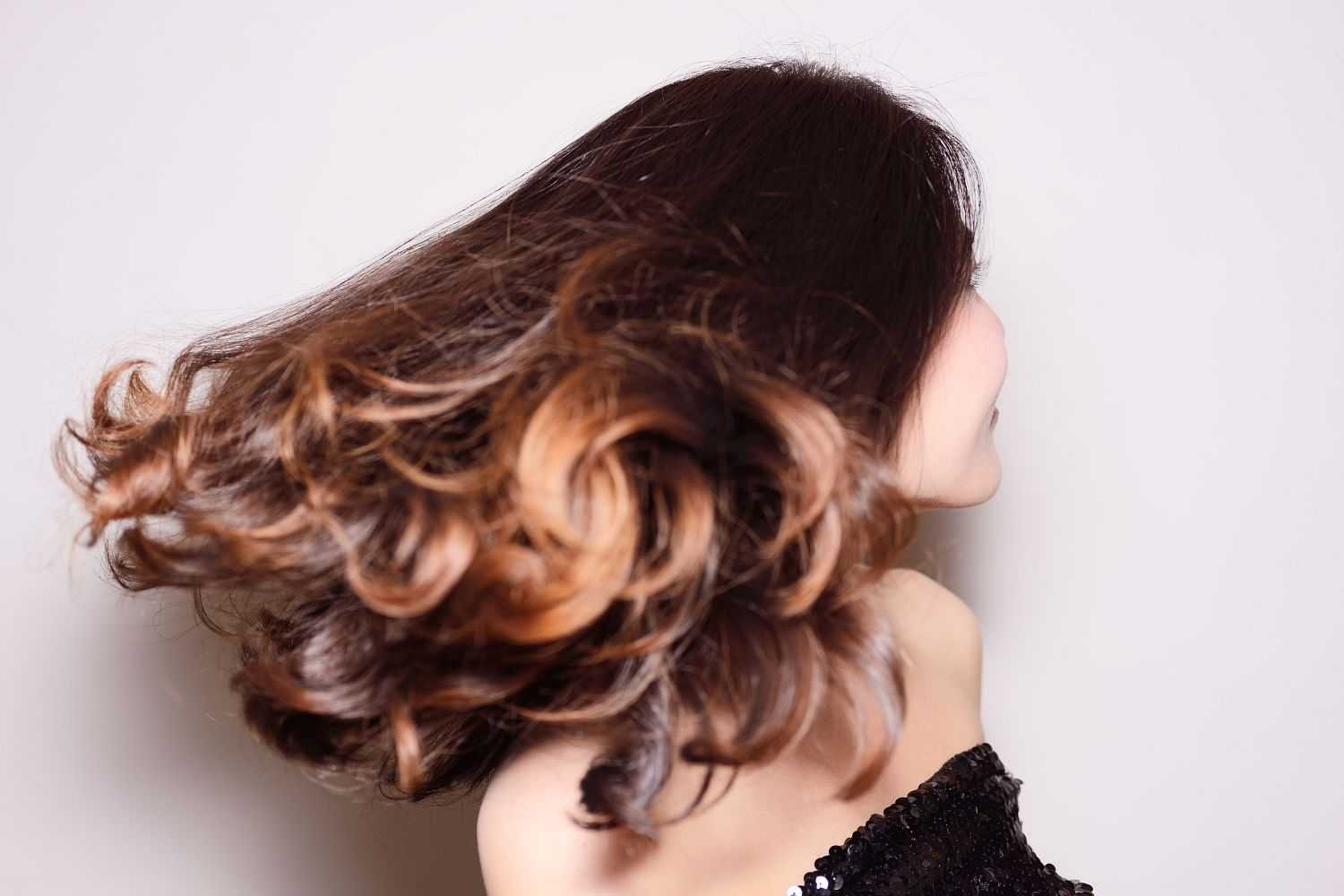 Woman with brown curly hair in motion against a light background.